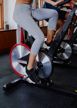 Spor kıyafetli genç çift ırklı kadın ve siyah adamın spor salonunda spor bisikleti sürerken yakın çekimi.