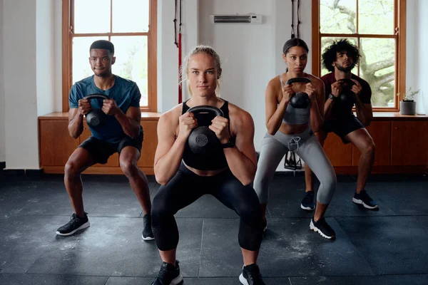 Grupa Dopasowanych Wielorasowych Młodych Dorosłych Odzieży Sportowej Robiących Przysiady Kettlebell — Zdjęcie stockowe