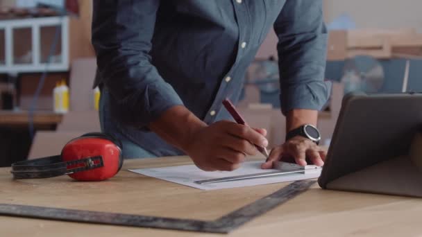 木工工場で働いている間に紙に書いている多人種の若者のクローズアップ — ストック動画