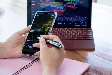 Yatırım yapmak için dizüstü bilgisayarlar, tabletler, akıllı telefonlar kullanma ve finansal tabloları evden görme kavramı.