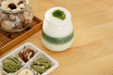 Sütlü Matcha Latte, ahşap bir yüzeye yerleştirilmiş kurabiye ve dekorasyonların yanına..