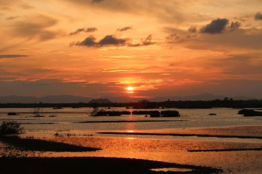 Güneş doğanın ve suyun üzerinde alacakaranlıkta batmak üzere..