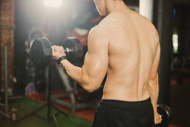 Kollarıyla dambılları kaldırırken Asyalı vücut geliştiricilerin sırt kasları.