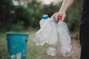 Bir adam elinde kullanılmış plastik bir şişe tutuyor..