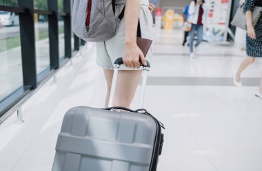 Havaalanında bavul taşıyan Asyalı kadın turist..