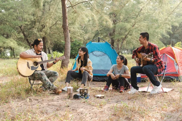 Ormanda, Asyalı erkek ve kadın gezginler kamp yapıyor, parti yapıyor, sohbet ediyor, şarkı söylüyor ve gitar çalıyorlar..