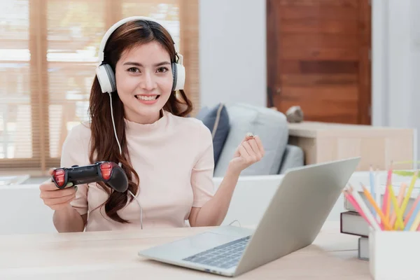 Güzel bir Asyalı kadın oyun oynamak için bir joystick taşıyor. Ev dizüstü bilgisayarını eğlence olarak kullanarak internete gir. Yeni normal bir hayat
