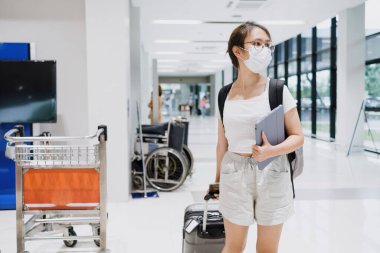 Havaalanında bavul taşıyan Asyalı kadın turist iş yerine gitmek için havaalanına gidiyor..