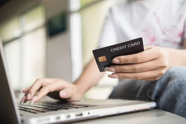 Woman entering credit card information to transact on website via laptop.