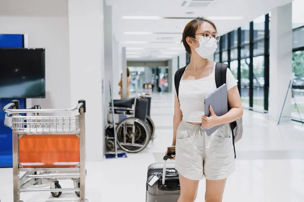 Havaalanında bavul taşıyan Asyalı kadın turist iş yerine gitmek için havaalanına gidiyor..