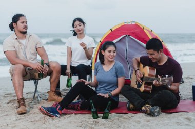 Açık hava turizmi, dört Asyalı erkek ve kadın kampı, şarkı söyleme ve gitar çalma.
