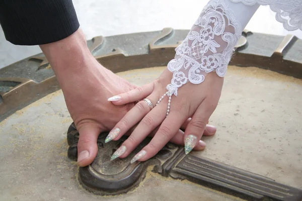 Bride and groom hands on a stone key — Stock Photo, Image