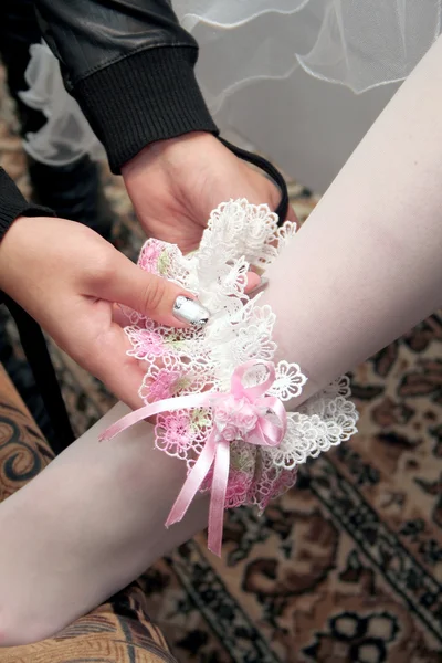 Bride putting on garter on her leg — Stock Photo, Image