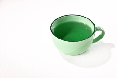 Bir fincan yeşil çay, masanın üstünde, beyaz arka planda doğal detoks..