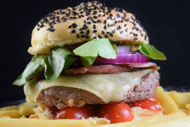 Susamlı hamburger sandviçi, soğanlı domates ve patates kızartması..