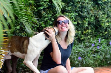 Genç sarışın kız, rahatça köpekle oynuyor.