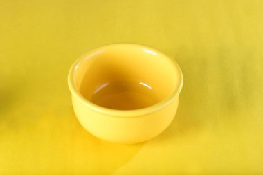 Sarı arka planda izole edilmiş sarı porselen kase, mutfak aletleri.