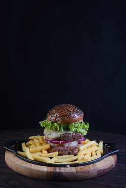 Susamlı hamburger sandviçi, soğanlı domates ve patates kızartması..