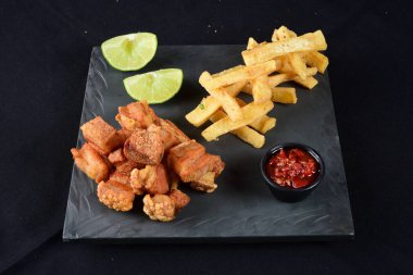 Kızarmış manyok ve limonlu domuz pastırması.