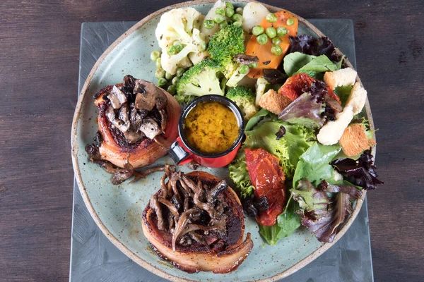 Domuz pastırmalı biftek, sebze salatası ve hardal soslu tabak.