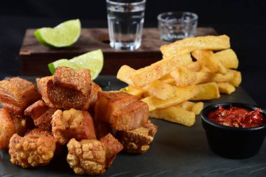 Kızarmış domuz derisi, kızarmış domuz pastırması, kızarmış manyok ve kırmızı sos, domuz göbeği.