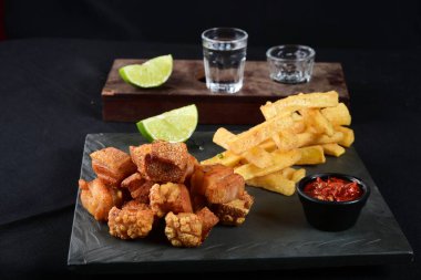 Kızarmış domuz derisi, kızarmış domuz pastırması, kızarmış manyok ve kırmızı sos, domuz göbeği.