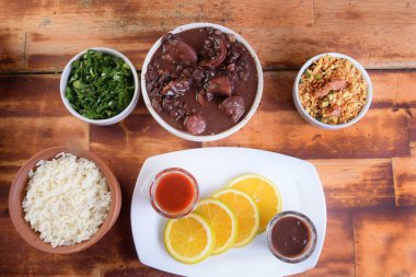 Feijoada tipik Brezilya yemeği, domuz pastırmalı fasulye, portakallı pirinç ve un, acı sos ve çıtırtı.