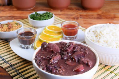 Feijoada tipik Brezilya yemeği, domuz pastırmalı fasulye, portakallı pirinç ve un, acı sos ve çıtırtı.
