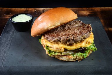 beef burger with bacon french fries cheese salad served with brioche bun.