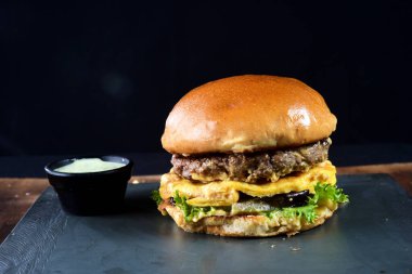 beef burger with bacon french fries cheese salad served with brioche bun.