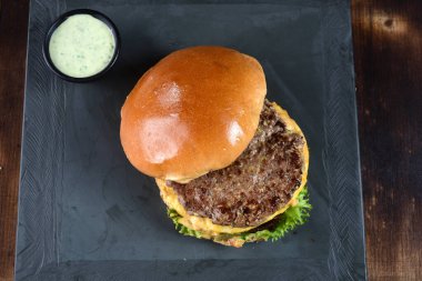 beef burger with bacon french fries cheese salad served with brioche bun.