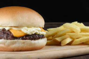 Pastırmalı burger sandviçi, salata, yumuşak yumurta ekmeği, siyah arka planda izole edilmiş ahşap masa.