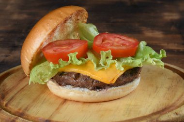 Pastırmalı burger sandviçi, salata, yumuşak yumurta ekmeği, siyah arka planda izole edilmiş ahşap masa.