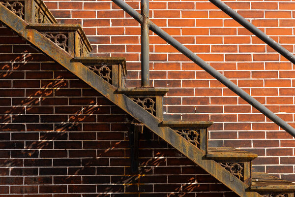 Old rusted metal staircase with brick wall in the background.