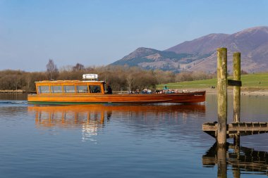 Keswick, İngiltere - Birleşik Krallık - 21 Mart 2022: Ahşap turist teknesi güzel bir bahar öğleden sonrasında Derwentwater 'da hareket ediyor.