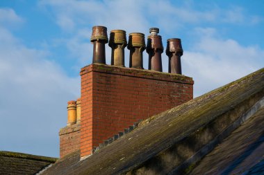 Çatıda eski tuğla baca ve arka planda bulutlar. Carlisle, İngiltere.