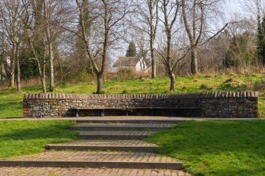 Güneşli bir bahar gününde ahşap bank ve taş duvar.