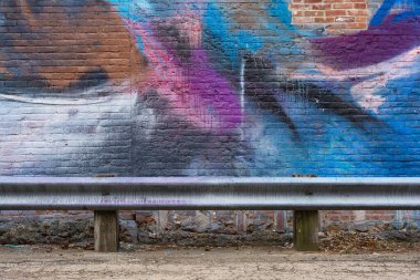 Orta batıdaki arka sokakta boyanmış tuğla duvar ve metal parmaklık..