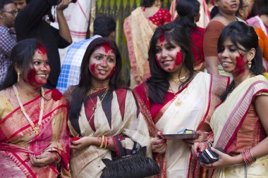Hindu women play with vermilion during durga puja clipart