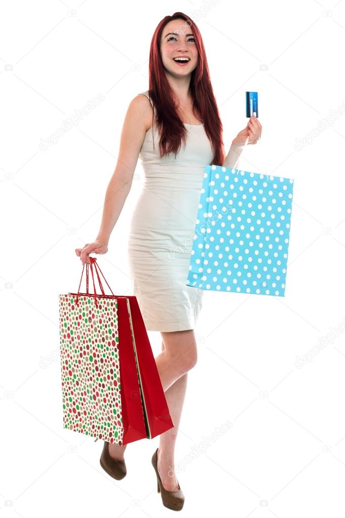 Happy red haired woman carying shopping bags