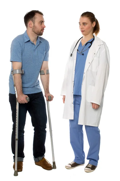 Man on crutches consulting with a doctor — Stock Photo, Image