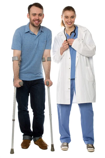 Man using crutches, next to a friendly physician — Stock Photo, Image