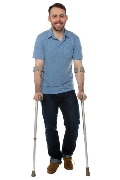 Smiling young man using crutches — Stock Photo, Image