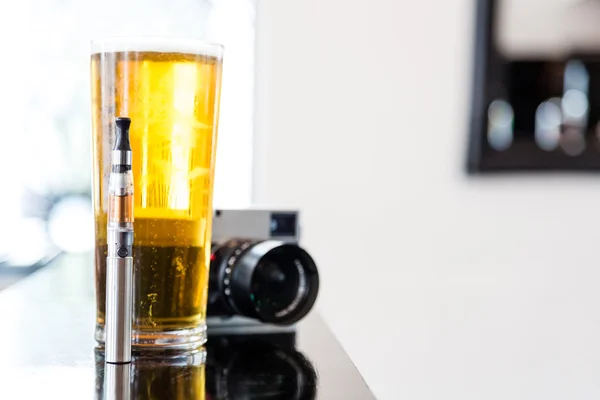 Una pinta de cerveza con un cigarrillo electrónico y una cámara — Foto de Stock