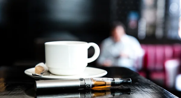E-sigaretta sdraiato su un bancone del bar con caffè — Foto Stock