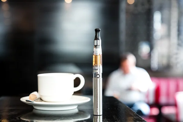 Caffè e sigaretta elettronica in un pub Fotografia Stock
