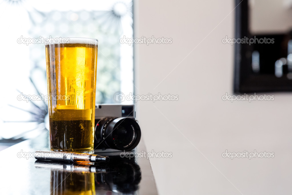 E-cigarette lying alongside beer and a camera