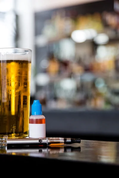 Glass of beer with electronic cigarette and juice — Stock Photo, Image