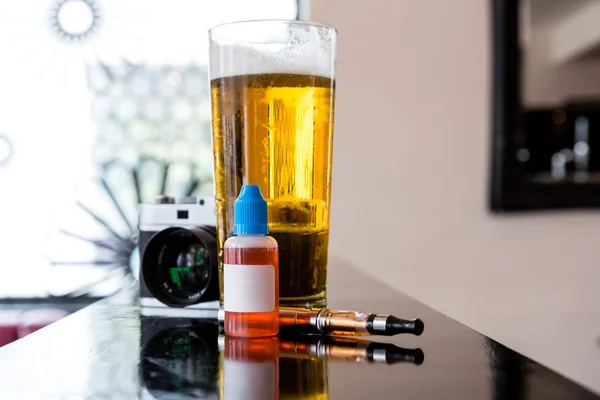 E-cigarette and refill bottle with a beer in a bar — Stock Photo, Image