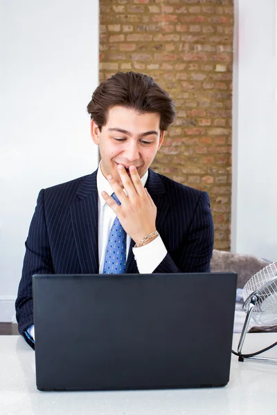 Geschäftsmann kichert an seinem Laptop — Stockfoto